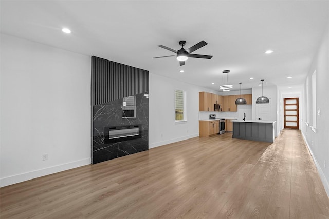 unfurnished living room with recessed lighting, baseboards, a ceiling fan, and light wood finished floors