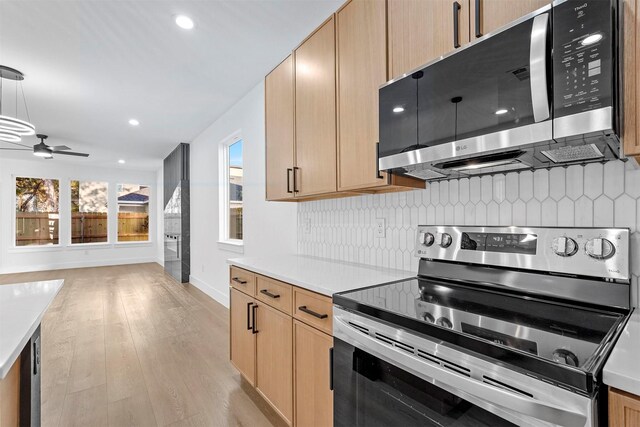 kitchen featuring decorative backsplash, ceiling fan, light wood-type flooring, light countertops, and appliances with stainless steel finishes
