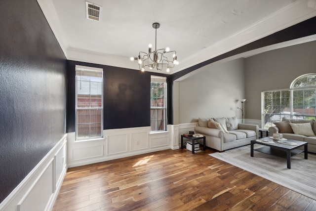 living area with arched walkways, wood-type flooring, a chandelier, and visible vents