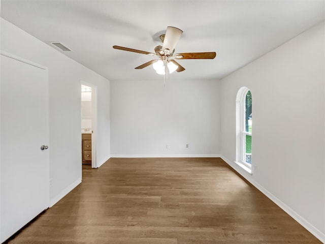 interior space with baseboards, arched walkways, wood finished floors, and visible vents