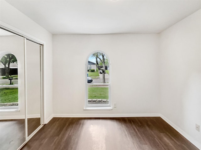 unfurnished room with baseboards and dark wood finished floors