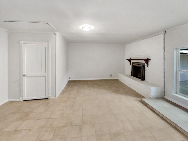 unfurnished living room with baseboards, a fireplace, and attic access
