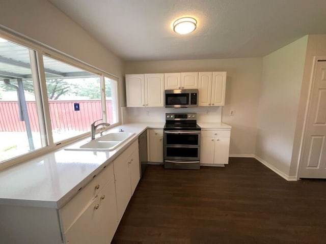 kitchen featuring dark wood-style flooring, a sink, light countertops, stainless steel appliances, and white cabinetry