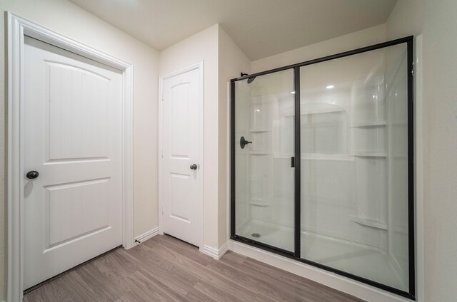 full bath with baseboards, a shower stall, and wood finished floors