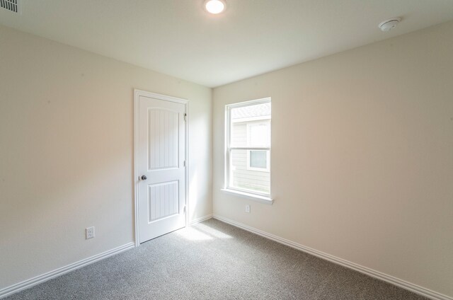 empty room with baseboards, visible vents, and carpet
