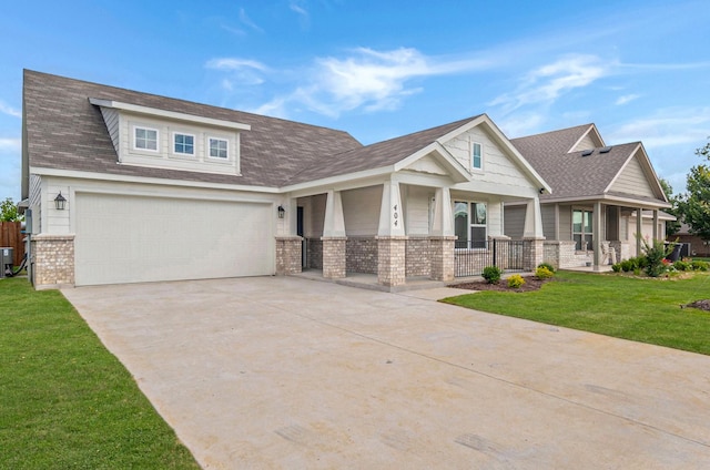 craftsman inspired home featuring a front yard, brick siding, a shingled roof, a porch, and driveway