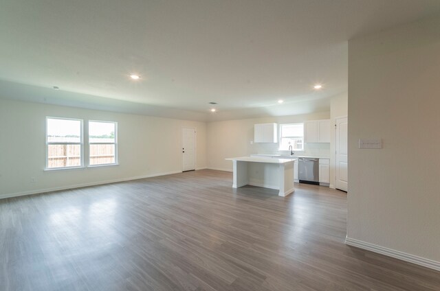 unfurnished living room with a sink, baseboards, recessed lighting, and wood finished floors