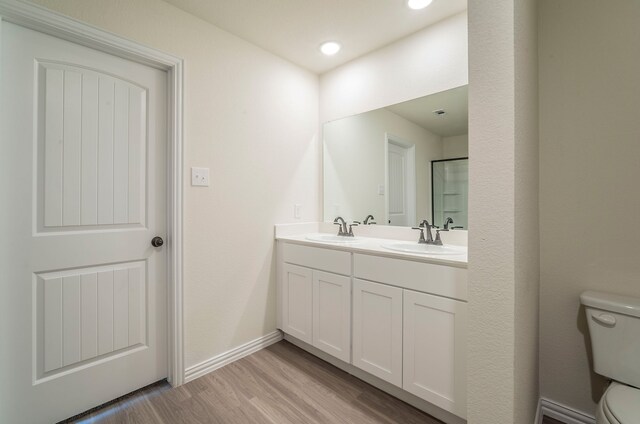bathroom featuring a sink, double vanity, toilet, and wood finished floors