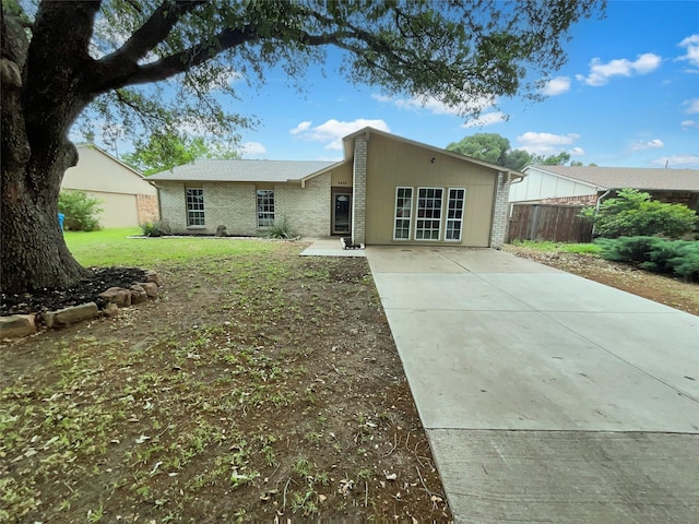 rear view of house with brick siding, a lawn, fence, and driveway