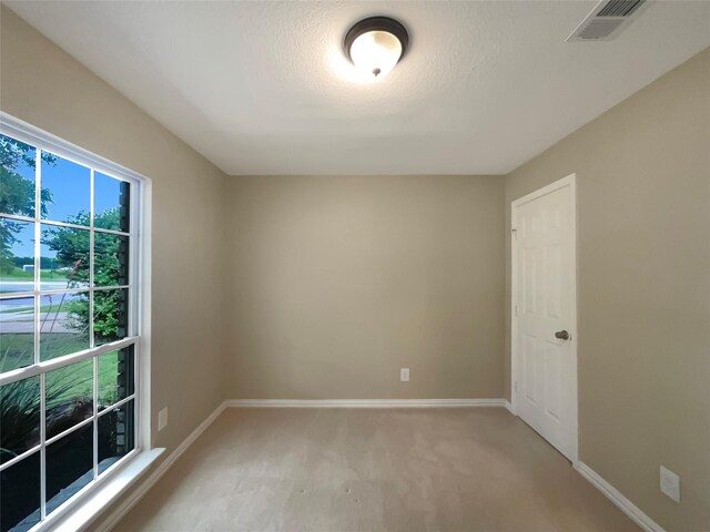 spare room featuring baseboards, light carpet, and visible vents