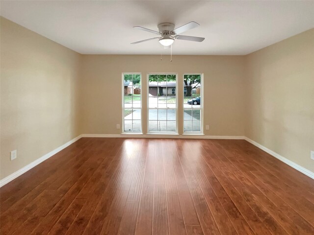 spare room with baseboards, ceiling fan, and wood finished floors