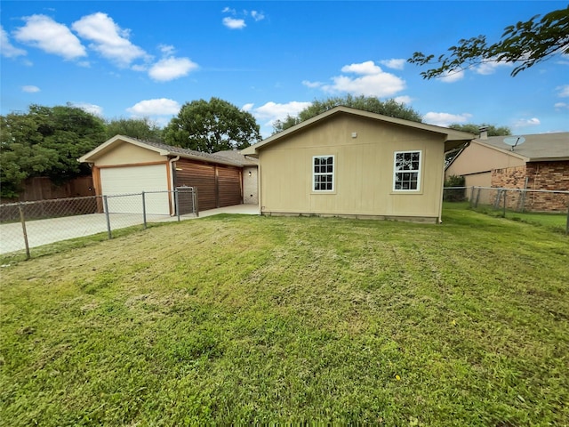 rear view of house featuring a garage, fence, a yard, and driveway