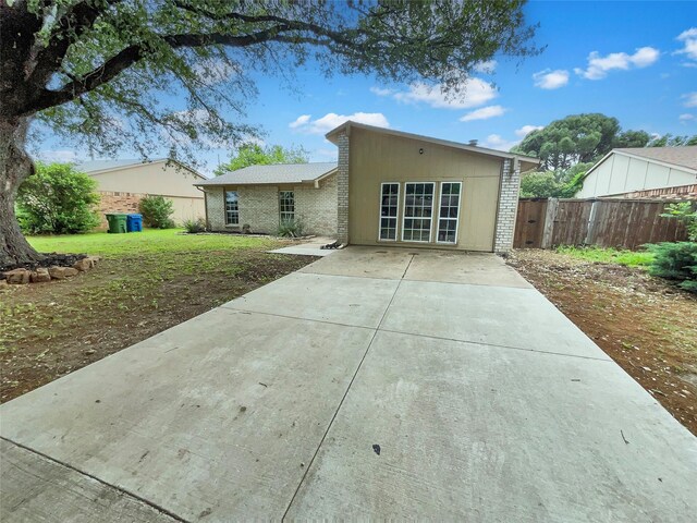 back of property featuring fence, a patio, and brick siding