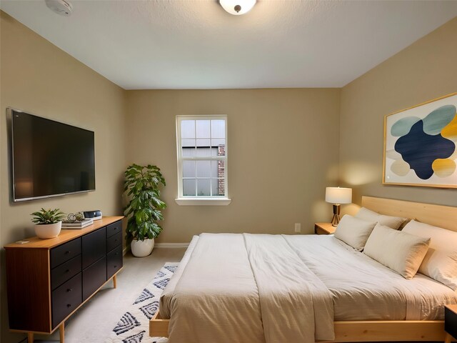 bedroom with baseboards and light carpet