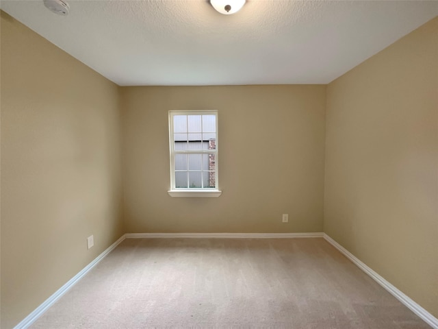 unfurnished room featuring a textured ceiling, baseboards, and carpet