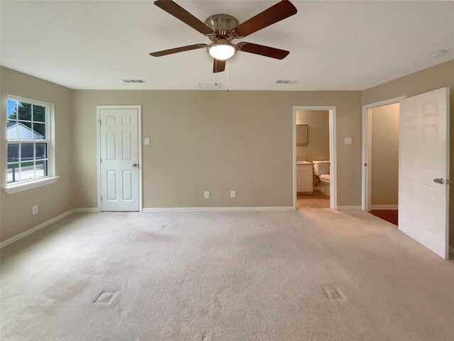 unfurnished bedroom featuring baseboards, light carpet, ensuite bath, and visible vents