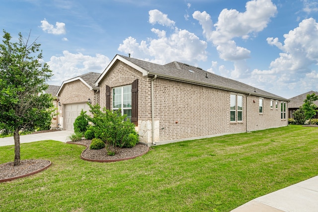 view of side of property with a garage, driveway, roof with shingles, brick siding, and a yard