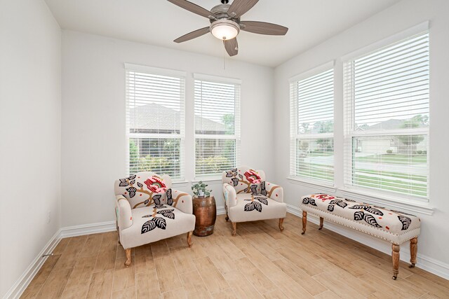 sitting room featuring a ceiling fan, baseboards, a wealth of natural light, and light wood-type flooring