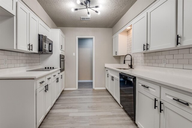 kitchen with visible vents, light countertops, a textured ceiling, a sink, and black appliances