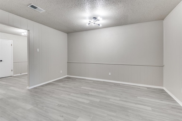 spare room with wood finished floors, baseboards, a textured ceiling, and visible vents
