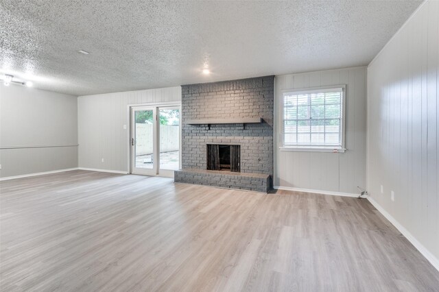 unfurnished living room featuring baseboards, a fireplace, a textured ceiling, and wood finished floors