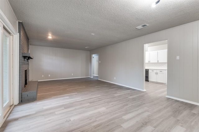 unfurnished living room featuring light wood-type flooring, a textured ceiling, visible vents, and a fireplace