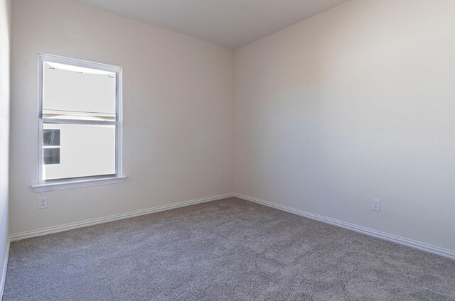 unfurnished room featuring carpet floors and baseboards