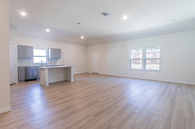 unfurnished living room featuring visible vents, a sink, light wood-style floors, and recessed lighting