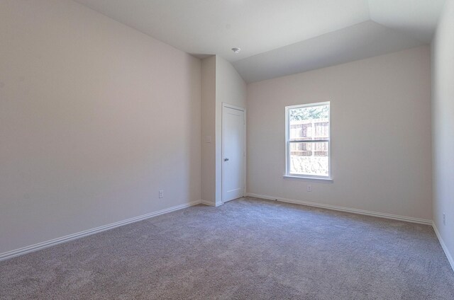 empty room with baseboards, carpet, and lofted ceiling