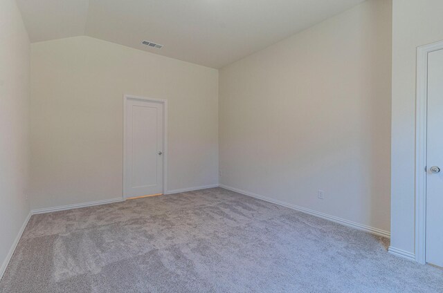 spare room featuring baseboards, vaulted ceiling, carpet flooring, and visible vents