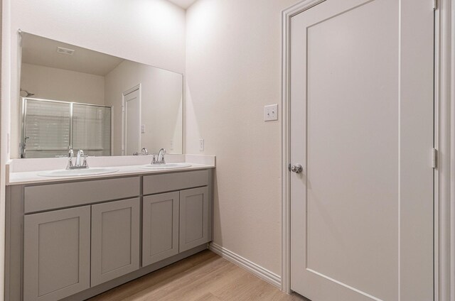 bathroom featuring double vanity, a sink, wood finished floors, and visible vents