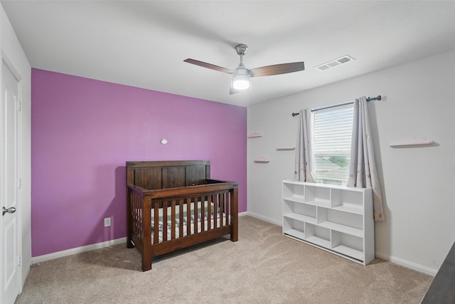 carpeted bedroom featuring baseboards, ceiling fan, and a crib
