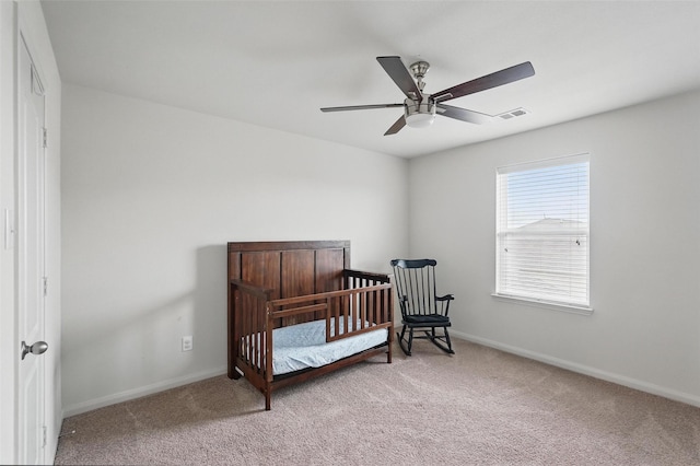 carpeted bedroom featuring baseboards, a ceiling fan, and a nursery area