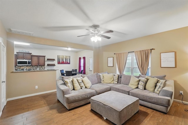 living area featuring light wood-style flooring, baseboards, plenty of natural light, and a ceiling fan