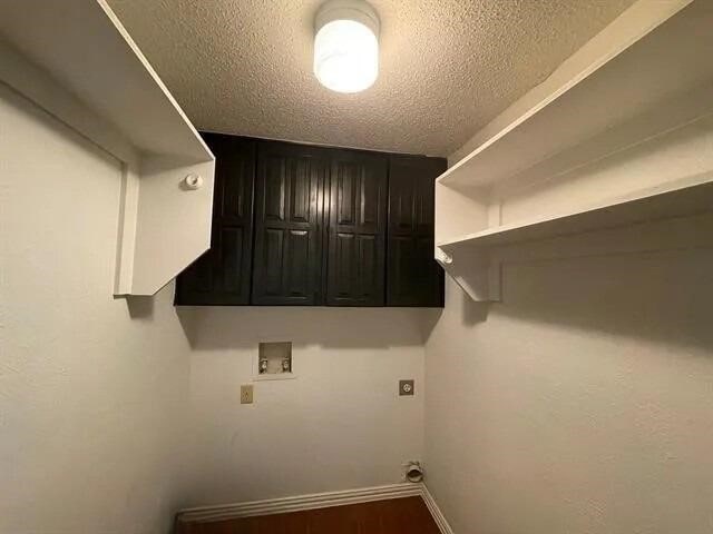 2406 Parkside Dr, Grand Prairie, TX 75052 - laundry room with baseboards, hookup for a washing machine, a textured ceiling, cabinet space, and hookup for an electric dryer