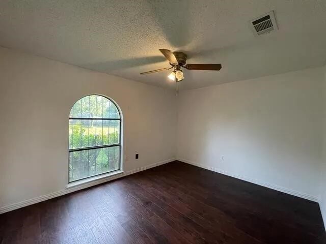 2406 Parkside Dr, Grand Prairie, TX 75052 - spare room with dark wood-style flooring, a ceiling fan, baseboards, and visible vents