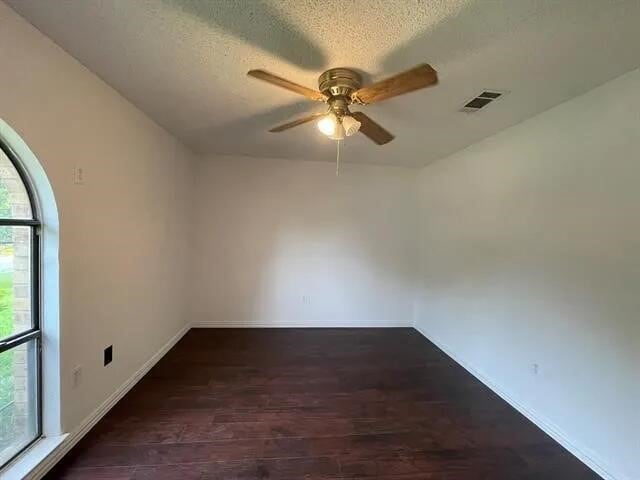 2406 Parkside Dr, Grand Prairie, TX 75052 - spare room featuring a healthy amount of sunlight, a ceiling fan, wood finished floors, and visible vents