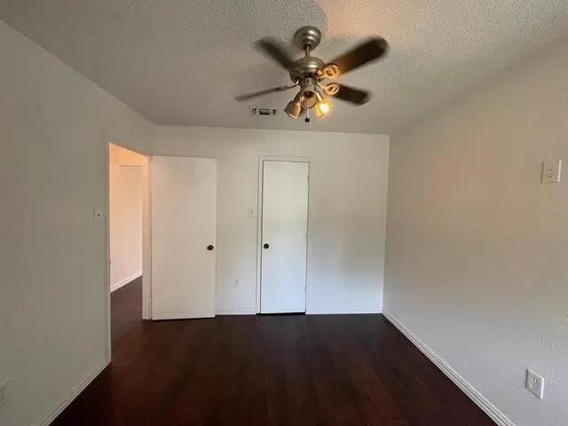 2406 Parkside Dr, Grand Prairie, TX 75052 - unfurnished bedroom featuring a textured ceiling, baseboards, and wood finished floors