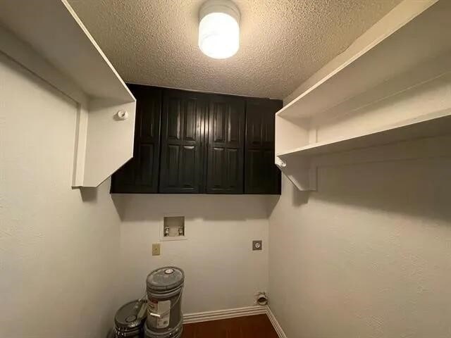 2406 Parkside Dr, Grand Prairie, TX 75052 - laundry room featuring washer hookup, hookup for an electric dryer, a textured ceiling, cabinet space, and baseboards