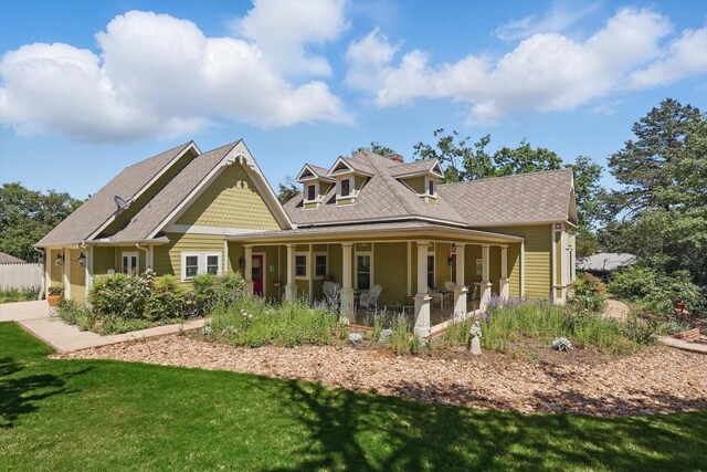 back of house with covered porch and a lawn