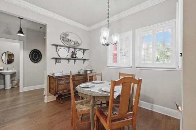 dining room featuring crown molding, a notable chandelier, baseboards, wood finished floors, and visible vents