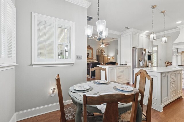 dining room featuring visible vents, a healthy amount of sunlight, ceiling fan with notable chandelier, and light wood-style floors