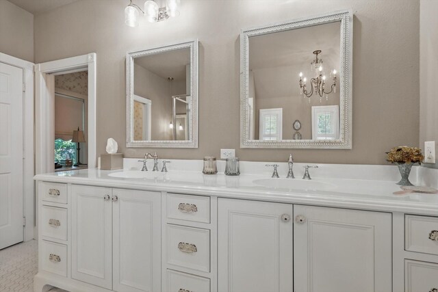 full bath featuring double vanity, an inviting chandelier, and a sink