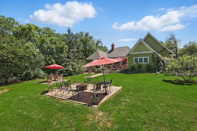 back of property with a lawn, a patio area, and an outdoor fire pit