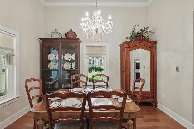 dining room with crown molding, dark wood-style flooring, baseboards, and an inviting chandelier