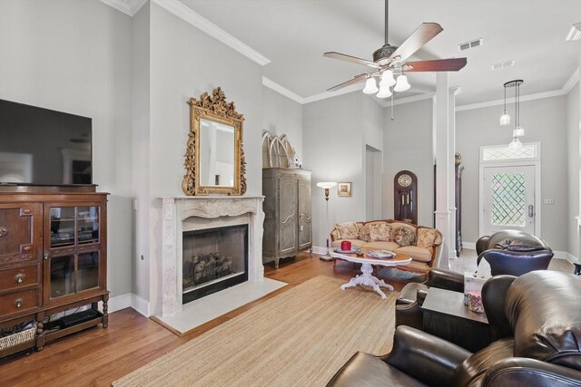 living area featuring visible vents, crown molding, wood finished floors, ceiling fan, and a premium fireplace