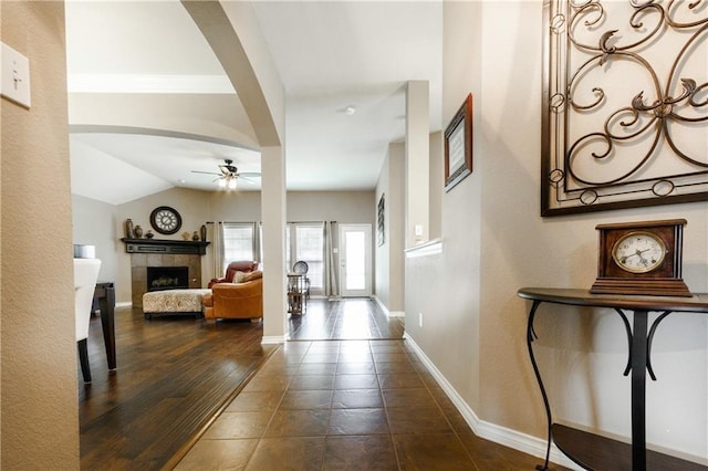 hallway featuring baseboards, arched walkways, and vaulted ceiling