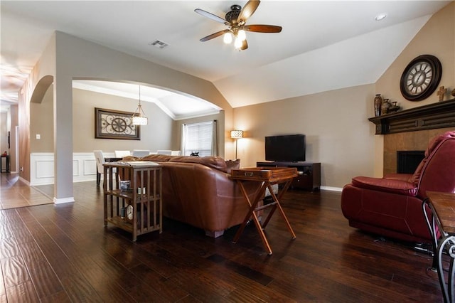 living area featuring visible vents, a ceiling fan, lofted ceiling, wood finished floors, and arched walkways
