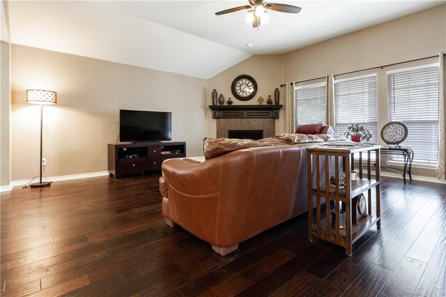 living room featuring a healthy amount of sunlight, ceiling fan, a tile fireplace, baseboards, and lofted ceiling