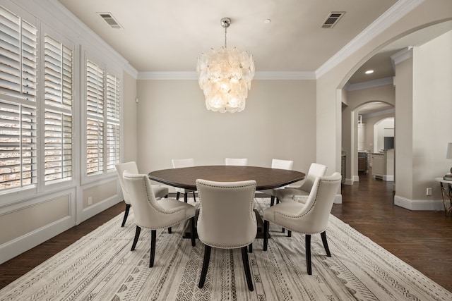 dining area featuring arched walkways, wood finished floors, a chandelier, baseboards, and ornamental molding